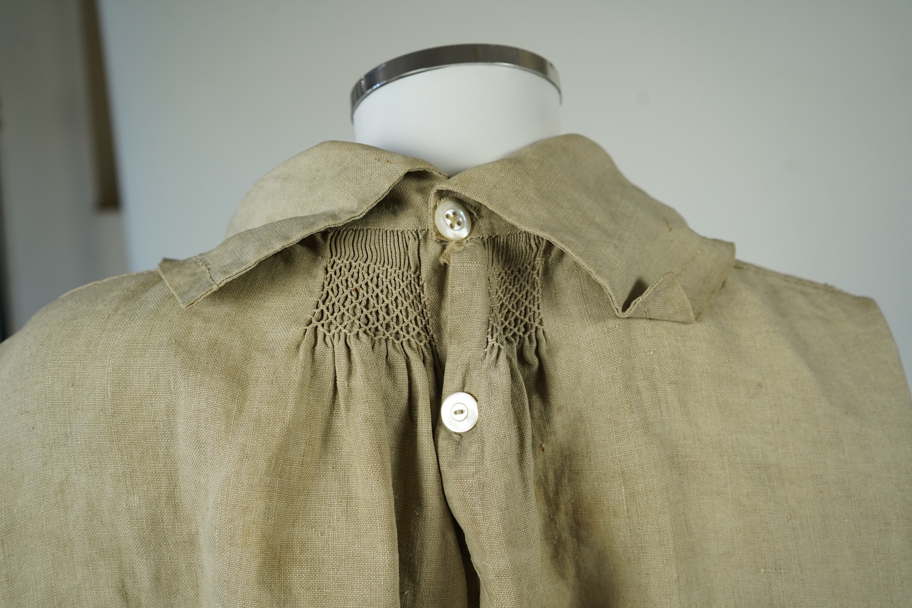 A 19th century heavy linen Shepherd’s smock, with small smocked shoulders and front and back neck panels under collar., 97cm long. Condition - patched and small darn near top and minor wear, usual for age and use.